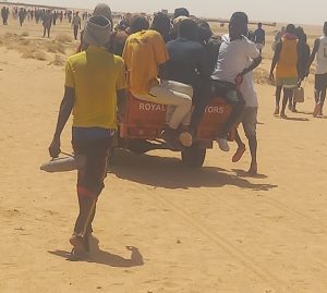 Menschen zu Fuß und auf einem Auto unterwegs in der Wüste