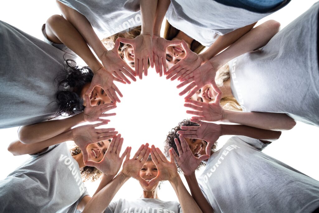 Gruppe von Menschen hält Hände in der Mitte zu einem Kreis zusammen