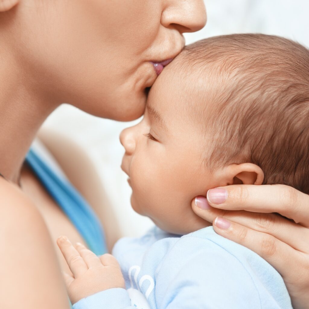 Mutter küsst ihr Neugeborenes auf die Stirn_alter_photo - stock.adobe.com